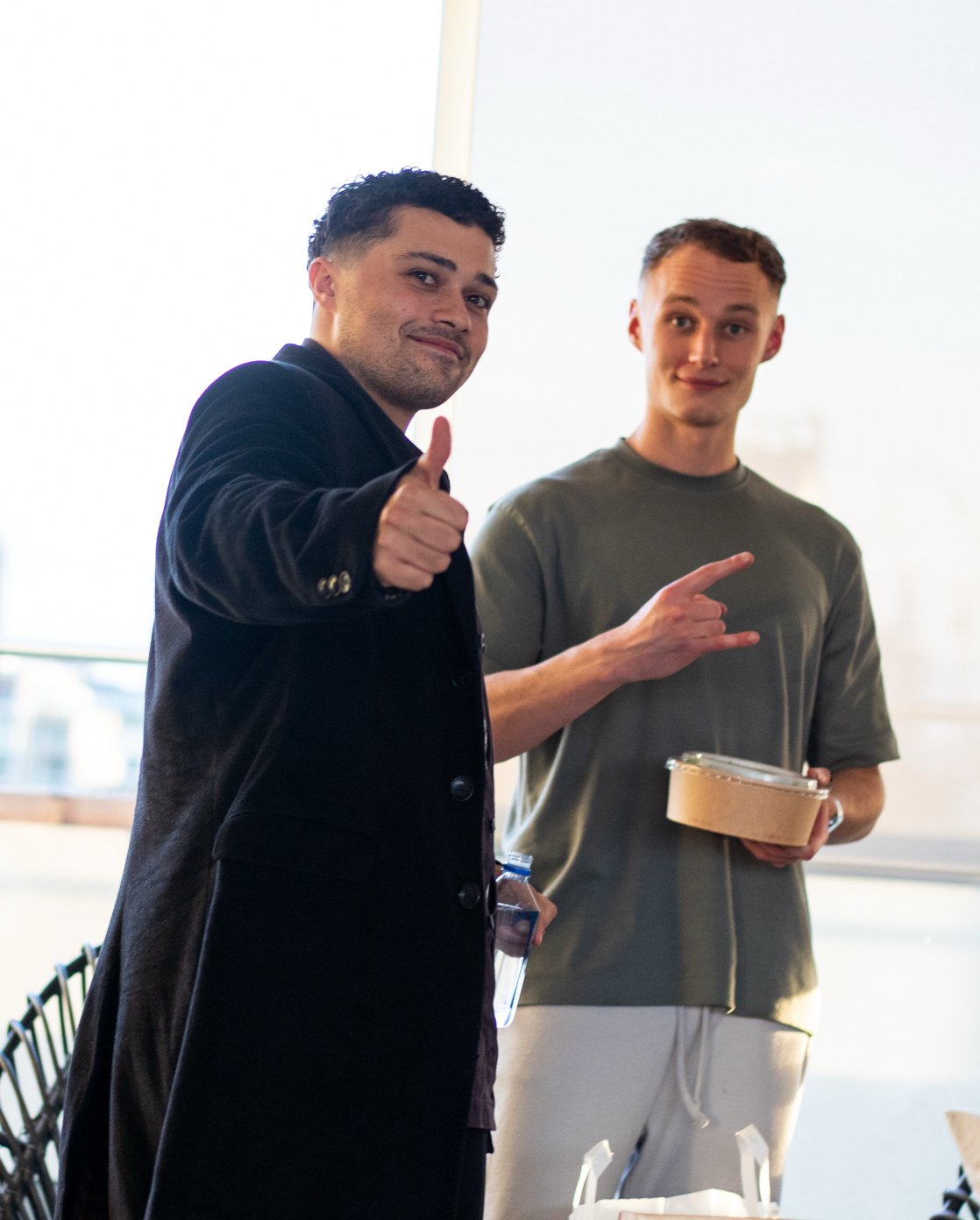 Charlie Morgan and Baudouin Borghans in a glass-walled apartment, casual clothes, takeout container