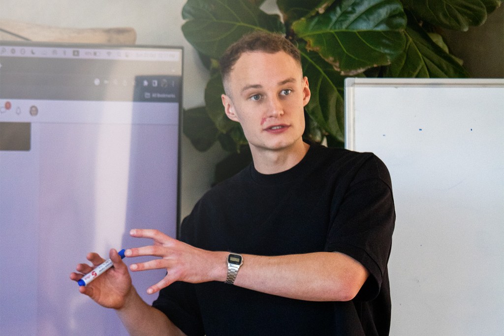 Charlie Morgan, co-founder of Imperium Acquisition, presenting in a black t-shirt with a whiteboard marker